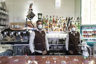 SALERNO, ITALY - MARCH 10: Two bartenders inside a bar wear masks and gloves on March 10, 2020 in Salerno, Italy. In Italy after the extension of the red zone to the entire peninsula due to the spread of the coronavirus, with considerable restrictions for all citizens and with the circulation permit only in case of work, health and for the purchase of primary goods, the bulletin updated by the Civil Protection has been released: Covid-19 counts 10,149 of which 1,004 were cured, while 631 people died after being positive for the virus. (Photo by Ivan Romano/Getty Images)