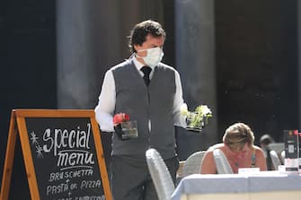 ROME, ITALY - MARCH 11: A waiter wearing protective mask sets a table  at the Pantheon Square on March 11, 2020 in Rome, Italy. The Italian Government has taken the unprecedented measure of a nationwide lockdown in an effort to fight the world's second-most deadly coronavirus outbreak outside of China. The movements in and out are allowed only for work and health reasons proven by a medical certificate. The justifications for the movements needs to be certified with a self-declaration by filling in forms provided by the police forces in charge of the checks. (Photo by Franco Origlia/Getty Images)
