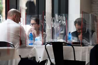 People have lunch at tables partitioned with plexiglas at the Goga Cafe on May 18, 2020 in central Milan during the country's lockdown aimed at curbing the spread of the COVID-19 infection, caused by the novel coronavirus. - Restaurants and churches reopen in Italy on May 18, 2020 as part of a fresh wave of lockdown easing in Europe and the country's latest step in a cautious, gradual return to normality, allowing businesses and churches to reopen after a two-month lockdown. (Photo by Miguel MEDINA / AFP) (Photo by MIGUEL MEDINA/AFP via Getty Images)