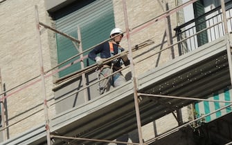 Un operaio edile sui ponteggi di un palazzo in ristrutturazione, 18 aprile 2017 a Genova.
ANSA/LUCA ZENNARO