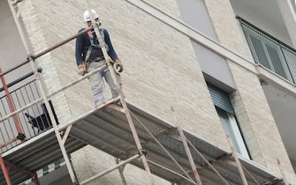 Un operaio edile sui ponteggi di un palazzo in ristrutturazione, 18 aprile 2017 a Genova.
ANSA/LUCA ZENNARO