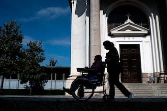 A nurse pushes an elderly resident in a wheelchair at the Tapparelli retirement home within visits of relatives on May 25, 2020 in Saluzzo near Cuneo, Piedmont, as the country eases lockdown measures taken to curb the spread of the COVID-19 pandemic, caused by the novel coronavirus. - the Tapparelli residence is home to 154 people, none of whom fell ill from the COVID-19. (Photo by MARCO BERTORELLO / AFP) (Photo by MARCO BERTORELLO/AFP via Getty Images)