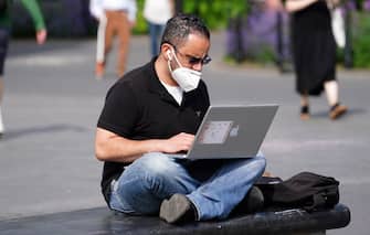NEW YORK, NEW YORK - MAY 27: A man wearing a protective mask uses a laptop in Washington Square Park during the coronavirus pandemic on May 27, 2020 in New York City. Government guidelines encourage wearing a mask in public with strong social distancing in effect as all 50 states in the USA have begun a gradual process to slowly reopen after weeks of stay-at-home measures to slow the spread of COVID-19. (Photo by Cindy Ord/Getty Images)