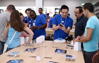 Employees show to customers Apple's iPhone 5 smartphones over iPads in a new Apple store on July 6, 2013 in Rosny-sous-Bois, near Paris. AFP PHOTO / THOMAS SAMSON        (Photo credit should read THOMAS SAMSON/AFP via Getty Images)