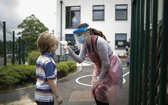 LONDON, ENGLAND - JUNE 04: A member of staff wearing personal protective equipment (PPE) takes a child's temperature at the Harris Academy's Shortland's school on June 04, 2020 in London, England. As part of Covid-19 lockdown measures, Harris Academy schools have taught smaller pods of students, to help maintain social distancing measures. With restrictions now lifting and the Government encouraging schools to re-open, the school staff has been working to find the best way to provide extra spaces while still retaining the correct social distancing measures and cleanliness requirements. This week, some schools across England reopened for some students, with children in reception, Year 1 and Year 6 allowed to return first. (Photo by Dan Kitwood/Getty Images)