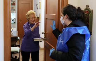ROME, ITALY - MARCH 16: Giulia Baini, 24, a volunteer from the Community of Sant'Egidio, speaks to Giovanna, a frail elderly woman of 82 years of age during a home-care service on March 16, 2020 in Rome, Italy. The Italian Government has taken the unprecedented measure of a nationwide lockdown by closing all businesses except essential services such as, pharmacies, grocery stores, hardware stores, tobacconists and banks, in an effort to fight the world's second-most deadly Coronavirus (COVID-19) outbreak outside of China. Journeys are allowed only for work reasons and health reasons proven by a medical certificate. Citizens are encourage to stay home and have an obligation to respect a safety distance of one metre from each other in supermarkets or in public spaces. (Photo by Marco Di Lauro/Getty Images)