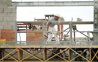 DES PLAINES, IL - AUGUST 05: A bricklayer shovels material while working on a new condominium building under construction August 5, 2005 in Des Plaines, Illinois. In a report released today, the US Labor Department reported that US employers added 207,000 jobs in July. (Photo by Tim Boyle/Getty Images)