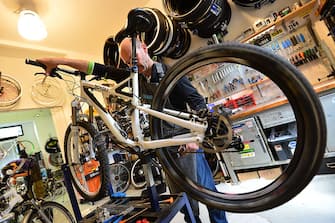 A mechanic repairs a bicycle in a workshop in Milan on May 21, 2013.  AFP PHOTO / GIUSEPPE CACACE        (Photo credit should read GIUSEPPE CACACE/AFP via Getty Images)