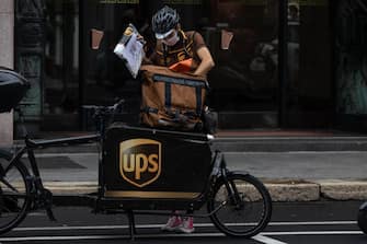 MILAN, ITALY - SEPTEMBER 23: A delivery man for United Parcel Service (UPS) handles a parcel next to his cargo bike on September 23, 2020 in Milan, Italy. Since the end of lockdown Milan authorities have added a further 35 kilometers of pop-up bike lanes and cycle paths and encouraged cycling and riding e-scooters as a safer form of transport away from jam-packed buses or subway trains, in order to promote social distancing in response to COVID-19. (Photo by Emanuele Cremaschi/Getty Images)