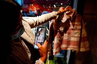 A woman uses her phone to scan a shirt inside the AliExpress pop-up store in Paris on September 24, 2020. - The global marketplace of Chinese e-commerce giant Alibaba, AliExpress, opened from September 24 to 26 a pop-up store in Paris for the first time in France, aiming to showcase its fashion and decoration products and its concept of "shoppertainment" in video streams. (Photo by GEOFFROY VAN DER HASSELT / AFP) (Photo by GEOFFROY VAN DER HASSELT/AFP via Getty Images)