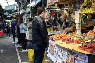 A customer wearing protective facemask and gloves waits to be serves at a fruit and vegetable of the local market in the district of Trionfale, in Rome, on April 16, 2020, during a strict lockdown of the country, aimed at curbing the spread of the COVID-19 epidemic caused by the novel coronavirus. (Photo by Andreas SOLARO / AFP) (Photo by ANDREAS SOLARO/AFP via Getty Images)