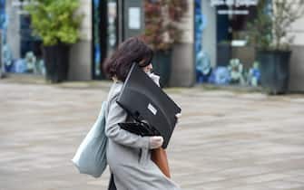 A woman carries a computer monitor for teleworking, in Nantes, western France, on March 17, 2020 while a strict lockdown comes into effect to stop the spread of the COVID-19 in the country. - A strict lockdown requiring most people in France to remain at home came into effect at midday on March 17, 2020, prohibiting all but essential outings in a bid to curb the coronavirus spread. The government has said tens of thousands of police will be patrolling streets and issuing fines of 38 to 135 euros ($42-$150) for people without a written declaration justifying their reasons for being out. (Photo by Sebastien SALOM-GOMIS / AFP) (Photo by SEBASTIEN SALOM-GOMIS/AFP via Getty Images)