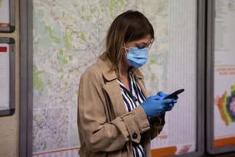 MILAN, ITALY - MAY 04: A woman wearing protective mask and gloves uses a mobile phone while waiting for a train at M1 underground line Cadorna station on May 04, 2020 in Milan, Italy. Starting today, more than 4 millions of Italians will get back to work as manufacturers, construction companies and some wholesalers re-open after two months of lockdown; people will also be allowed to exercise outdoor and to visit family members living in the same region, as long as they will respect social distancing. Italy was the first country to impose a nationwide lockdown to stem the transmission of the Coronavirus (COVID-19), and its restaurants, theaters and many other businesses remain closed. (Photo by Emanuele Cremaschi/Getty Images)