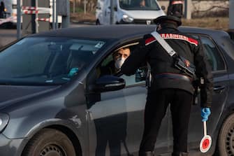 GUARDAMIGLIO, ITALY - FEBRUARY 24: An Italian Carabinieri officer, wearing a respiratory mask, talks to a driver at a road block on February 24, 2020 in Guardamiglio, south-west Milan, Italy. Guardamiglio is a town nearby one of the ten small towns placed under lockdown after coronavirus sparked infections throughout the Lombardy region. Italy is the last country to be hit hard by the virus with 6 dead and more than 229 infected as of today. The spread marks Europeâ  s biggest outbreak, prompting Italian Government to issue draconian safety measures. (Photo by Emanuele Cremaschi/Getty Images)