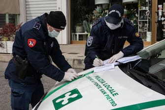 PONTE SAN PIETRO, ITALY - MARCH 27: Two local Police officers rill a self-declaration form provided by a driver (not in the picture) at a checkpoint on March 27, 2020 in Ponte San Pietro, near Bergamo, Northern Italy. Bergamo and its nearby towns are the epicenter of Italyâ  s hardest-hit region, Lombardy, the site of hundreds of coronavirus deaths. The Italian government continues to enforce the nationwide lockdown measures to control the spread of COVID-19. (Photo by Emanuele Cremaschi/Getty Images)