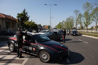 MILAN, ITALY - APRIL 10: Italian Carabinieri officers, wearing respiratory masks, stand guard at a road block on April 10, 2020 in Milan, Italy. The Italian Government has further strengthened police controls nationwide, in the effort to prevent people leaving the quarantine as the long Easter weekend begins. There have been well over 140,000 reported COVID-19 cases in Italy and more than 18,000 related deaths, but the officials are confident the peak of new cases has passed. (Photo by Emanuele Cremaschi/Getty Images)