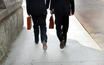 Due uomini con la valigetta 24 ore mentre si recano al lavoro