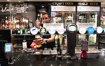 epa08526175 A worker serves a pint in a pub in Soho London, Britain, 04 July 2020. Pubs, restaurants, places of worship and other businesses reopen their doors across the UK on 04 July after more than three months of lockdown due to coronavirus pandemic.  EPA/FACUNDO ARRIZABALAGA
