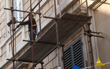 Un operaio edile su ponteggi intento a montare la ponteggiatura in un palazzo in ristrutturazione, Genova, 12 aprile 2017.
ANSA/LUCA ZENNARO