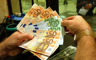 Due mani con banconote da 50 e 100 euro