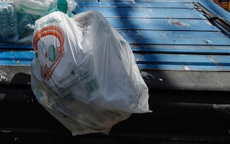 Un sacchetto pieno di spazzatura vicino a un cassonetto a Roma