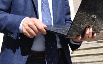 Un uomin in giacca e cravatta legge documenti al pc mentre è in giro 