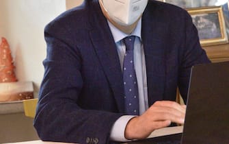 Un uomo con mascherina anti-Covid davanti al computer mentre lavora in smart working