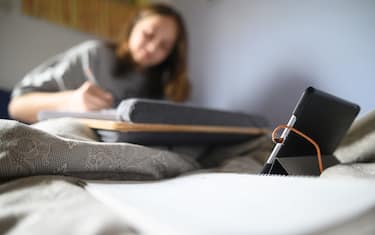 26 March 2020, Baden-Wuerttemberg, Waldenbuch: A student works for the school behind a tablet in her bed. To slow the spread of the coronavirus, the schools are closed. Therefore, students now work from home with digital aids. Photo: Sebastian Gollnow/dpa