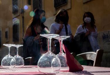 Woman wearing protective face masks walk past a terrace of a restaurant in Trastevere in central Rome on June 5, 2020, as bars and restaurants reopened after months-long closures aimed at stemming the spread of the COVID-19 pandemic, caused by the novel coronavirus. (Photo by Tiziana FABI / AFP) (Photo by TIZIANA FABI/AFP via Getty Images)