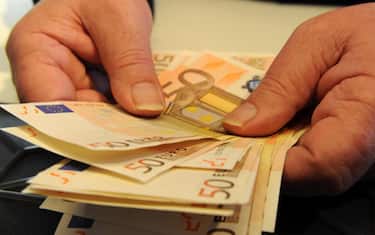 Una persona conta alcune banconote in una banca, Pisa, 15 maggio 2012. ANSA / FRANCO SILVI