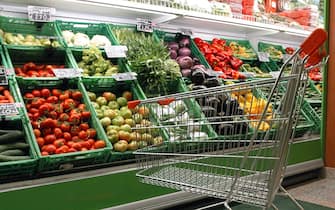 Un carrello davanti al banco frutta e verdura di un supermercato