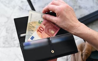 Un uomo tira fuori due banconote dal portafoglio