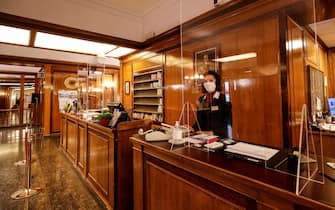 A receptionist work at Massimo D'Azeglio hotel wearing a protective face mask during of the emergency due to the Coronavirus Covid-19, in Rome, Italy, 22 April 2020. ANSA/GIUSEPPE LAMI