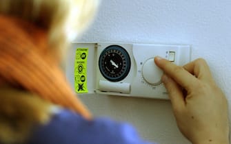 Donna regola la temperatura interna a casa attraverso il termostato