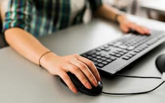 Close up of a woman using a computer keyboard and a mouse