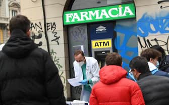Un farmacista consegna all'esterno di una farmacia del centro di Milano l'esito dei tamponi rapidi, 3 gennaio 2022. ANSA/DANIEL DAL ZENNARO