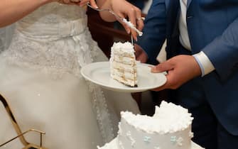 Newlyweds cut a beautiful white wedding cake.