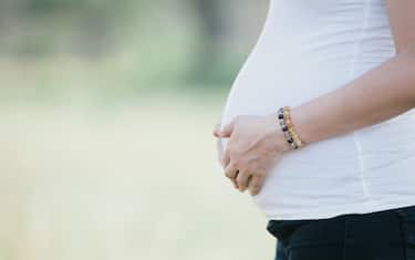 Pregnant woman holding her belly at outdoor location