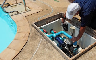 Technician fixing swimming pool water pump. Service and maintenance for swimming pool.