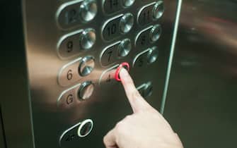 A person is pressing the elevator button with left hand