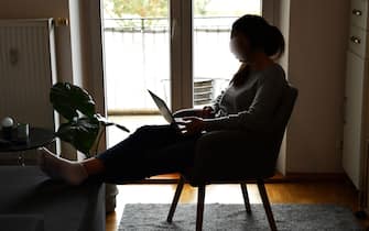 A young woman sits in her apartment with a laptop and works in the home office because of the corona pandemic.Silhouette, MODEL RELEASED! | usage worldwide