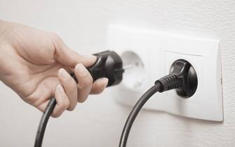 Woman pluging cable to the electric outlet