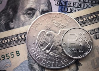 A Russian ruble coin is pictured with US dollar bills and a one dollar coin in Moscow, on March 15, 2022. - Russia has suspended the sale of foreign currencies until September 9, the central bank said in a statement, amid unprecedented economic sanctions on the country following its offensive in Ukraine. (Photo by AFP) (Photo by -/AFP via Getty Images)