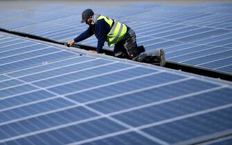 A worker fixes solar panels at a floating photovoltaic plant on the Silbersee lake in Haltern, western Germany, on April 22, 2022. - Germany's largest floating solar park is currently being built and will produce almost three million kilowatt hours of electricity per year. (Photo by Ina FASSBENDER / AFP) (Photo by INA FASSBENDER/AFP via Getty Images)