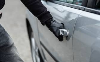 Close up on car thief hand pulling the handle of a car. Car thief, car theft concept