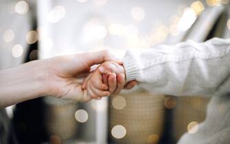 Close-up of adult and baby toddler hands holding as a symbol of care, love and help. Togetherness and role of family and parents in a life of a child. Copy space