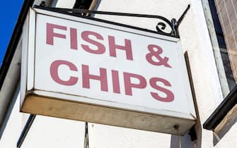 Sign for Fish and Chips on wall outside chip shop, Harwich, Essex, England, UK. (Photo by: Geography Photos/Universal Images Group via Getty Images)