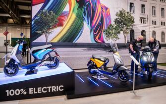 Visitors look at models of Piaggio 1 electric scooters on display at EICMA, the 78th edition of the International Bicycle and Motorcycle exhibition during its opening on November 23, 2021 in Milan. (Photo by Piero CRUCIATTI / AFP) (Photo by PIERO CRUCIATTI/AFP via Getty Images)