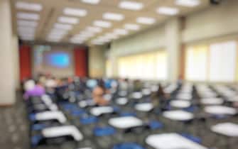 blurred image of empty large examination room with wooden chairs style. no people