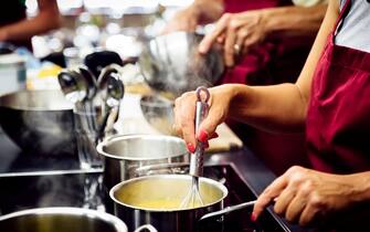 Womans hands stiring a hot sauce in a pan.